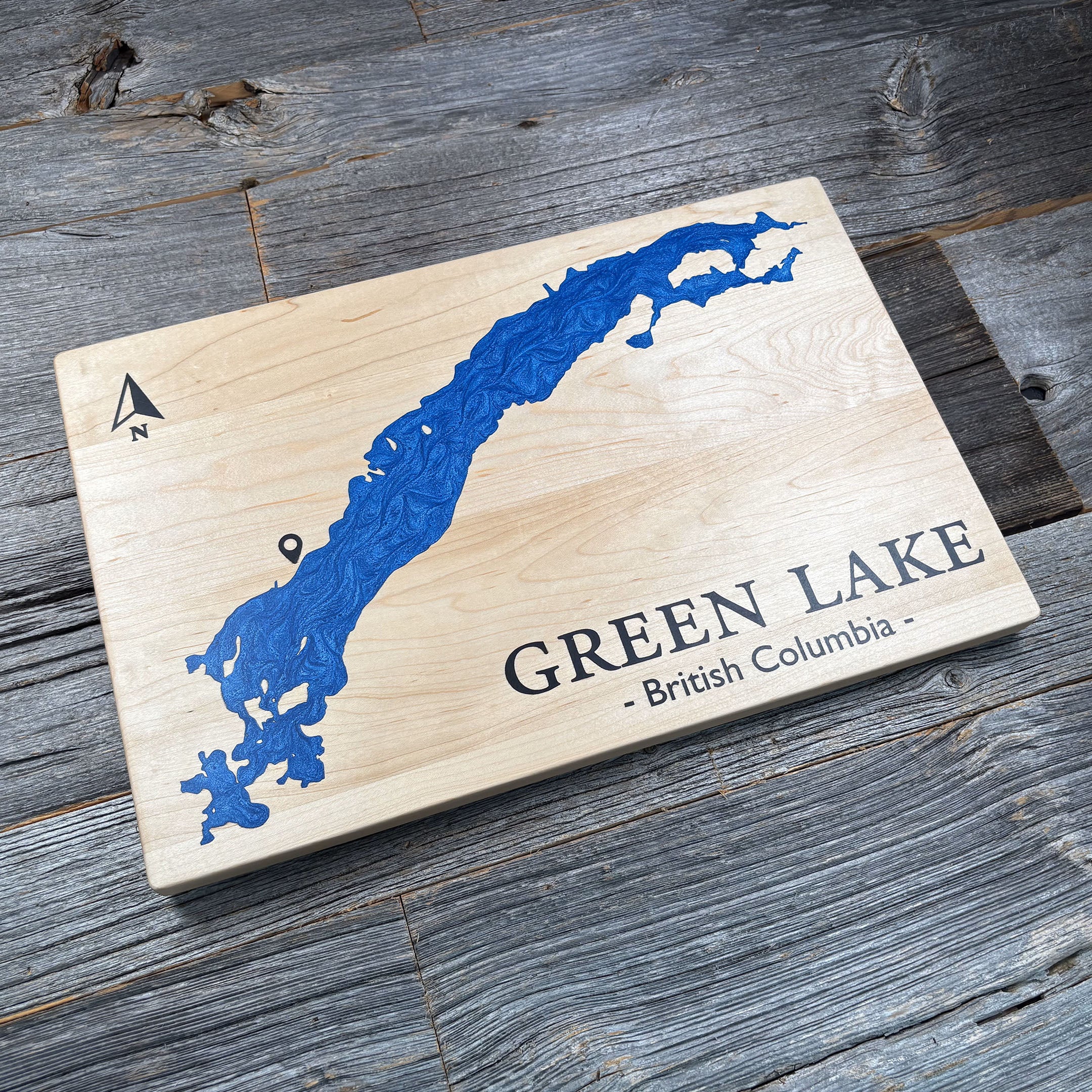 Custom maple wood wall art featuring a blue resin inlay map of Green Lake, British Columbia, with a compass rose and location marker, displayed on a rustic wooden background