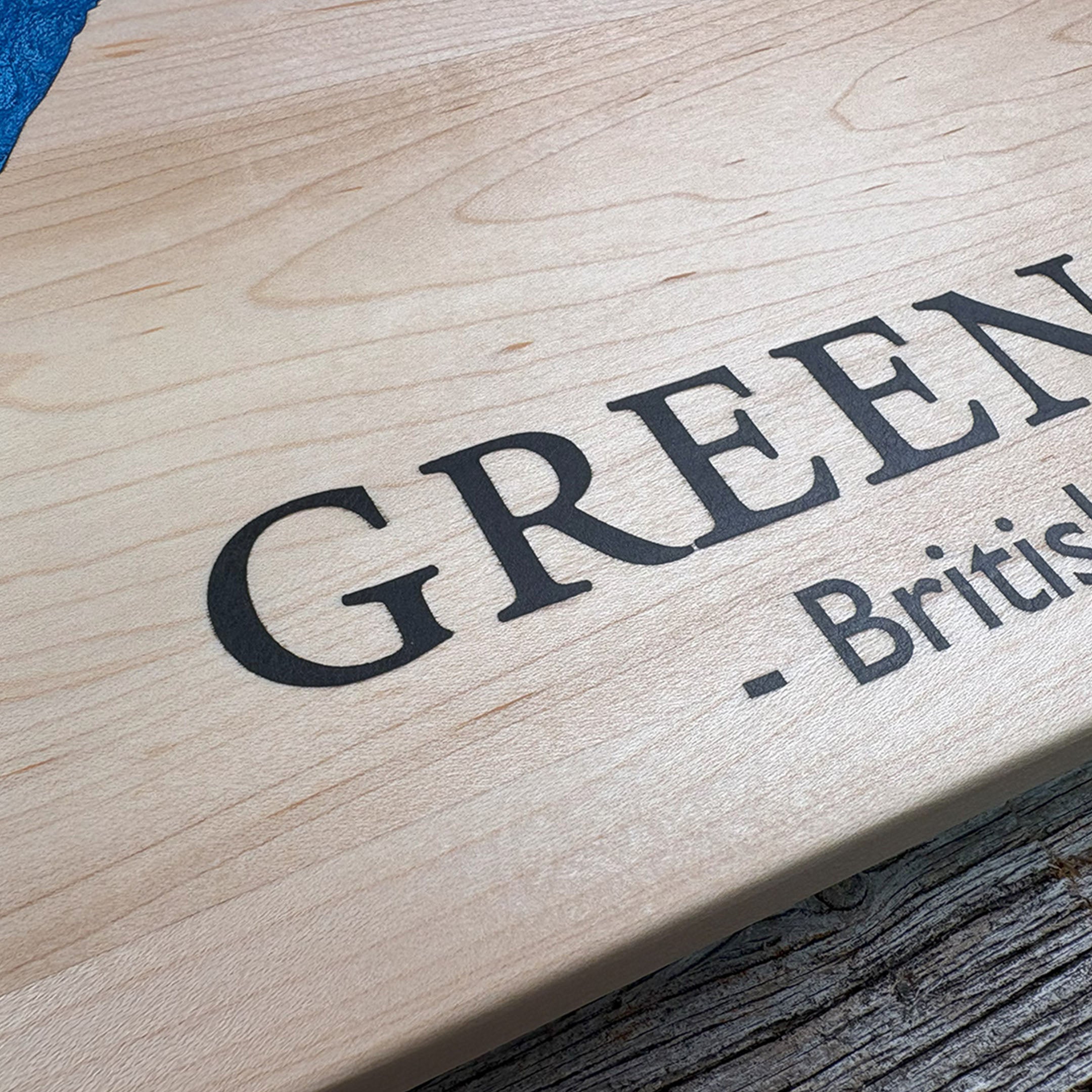 Close-up of custom maple wood wall art featuring the engraved text 'Green Lake - British Columbia,' highlighting precise craftsmanship and smooth wood grain