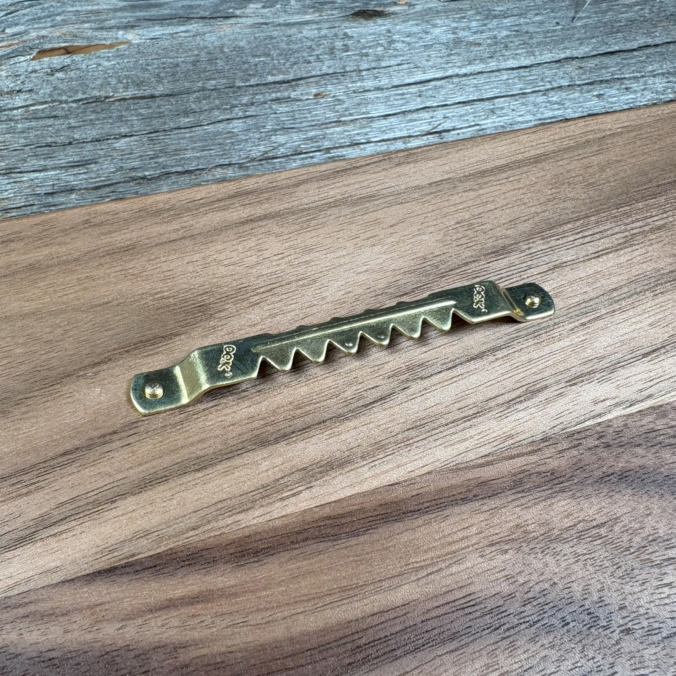 Close-up of a brass sawtooth hanger mounted on the backside of custom walnut wood wall art, highlighting the secure hanging hardware and smooth wood grain