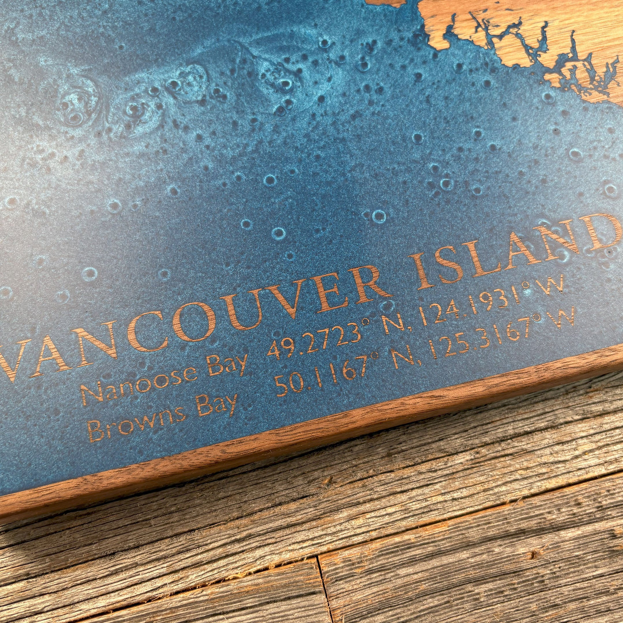 Custom walnut wood wall art featuring a blue resin inlay map of Vancouver Island with engraved coordinates for Nanoose Bay and Browns Bay, showcasing detailed craftsmanship and natural wood texture